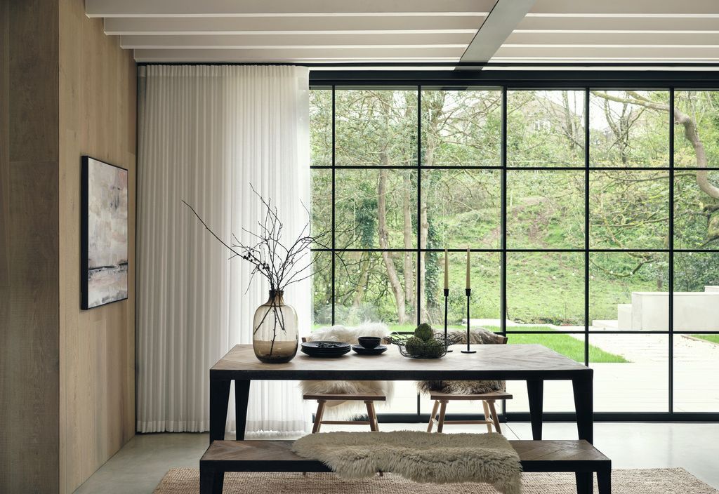 Wave curtains partly open alongside black Crittall glazing