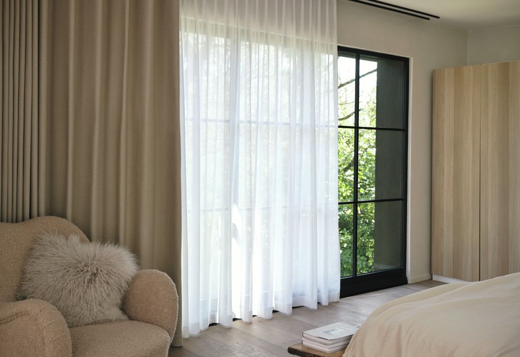 Bedroom with dual-layer curtains — sheer and blackout — on black Crittall doors