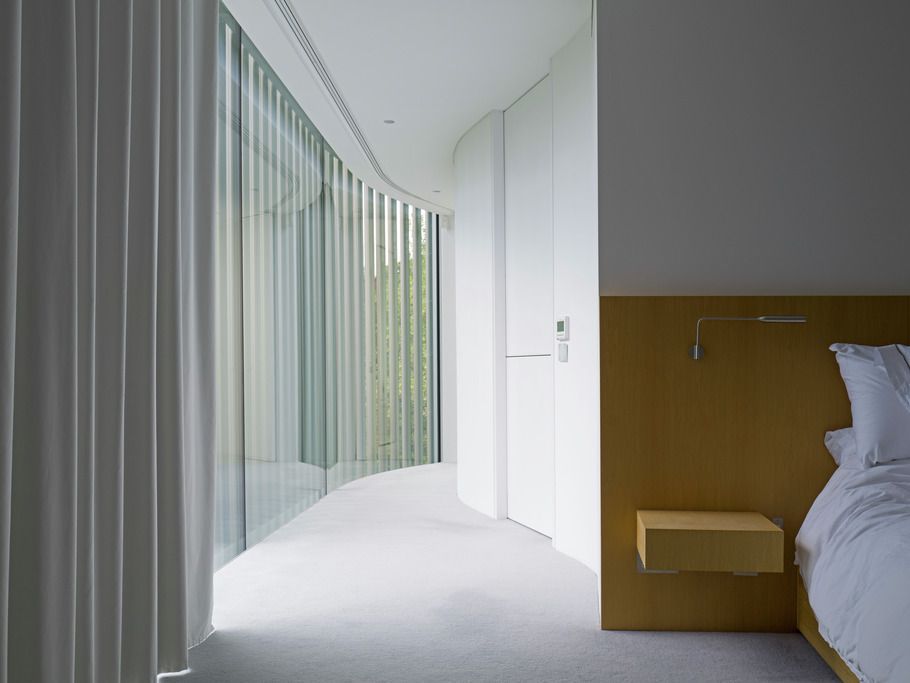 Sheer curtains following the curved glass wall in the bedroom