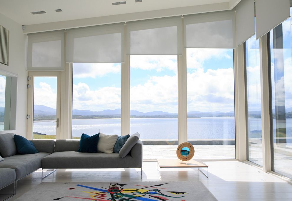 Full-width roller blinds filtering light with mountain and coastal panorama