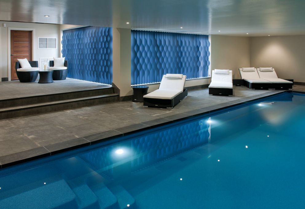 Indoor pool with floor-length blue curtains framing sea views