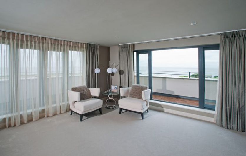 Master bedroom with sheer and blackout curtains overlooking the sea