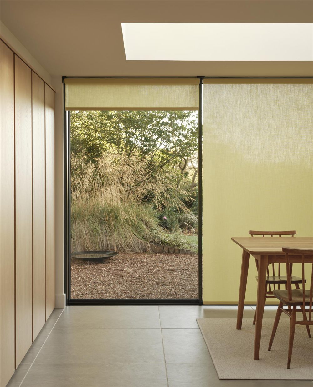 4955 roller blind in a contemporary dining room with garden views Silent Gliss 4955 battery roller blind in yellow Colorama fabric in a modern dining room